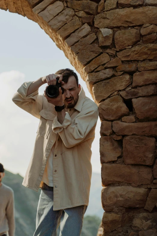 a man taking a picture of another man with a camera, at the stone ruins, paul thomas anderson, looking out, portrait featured on unsplash