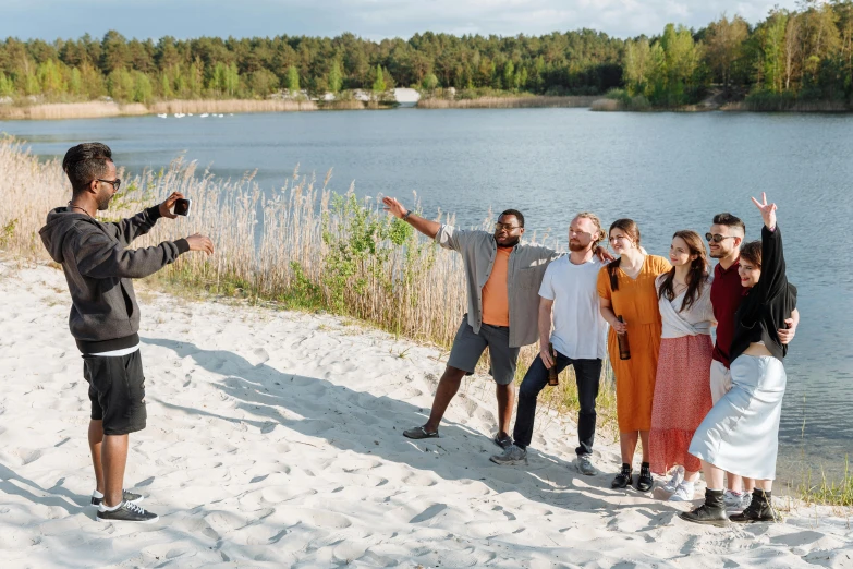 a group of people standing on top of a sandy beach, by Jesper Knudsen, hurufiyya, meet the actor behind the scenes, in a park and next to a lake, worship, influencer