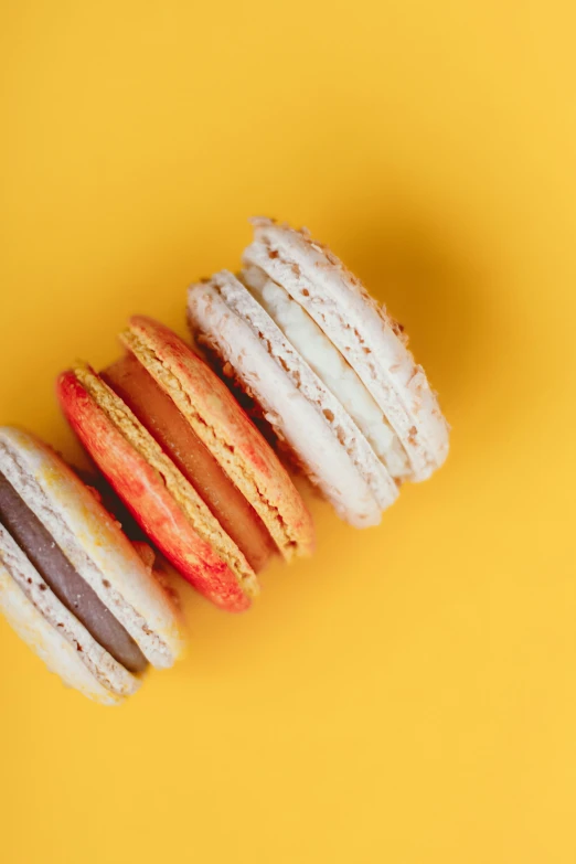 a stack of macarons on a yellow background, inspired by Richmond Barthé, pexels, nacre colors, yellow and red, made of food, on white background