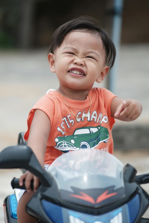 a little boy that is sitting on a motorcycle, by Yi Insang, happening, earing a shirt laughing, nivanh chanthara, slightly smirking, square