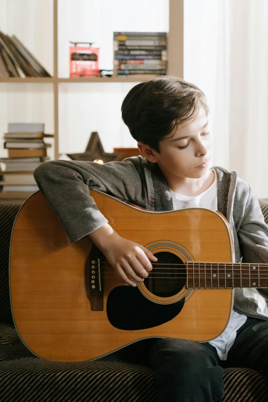 a boy sitting on a couch playing a guitar, compassionate, thumbnail, multiple stories, premium quality