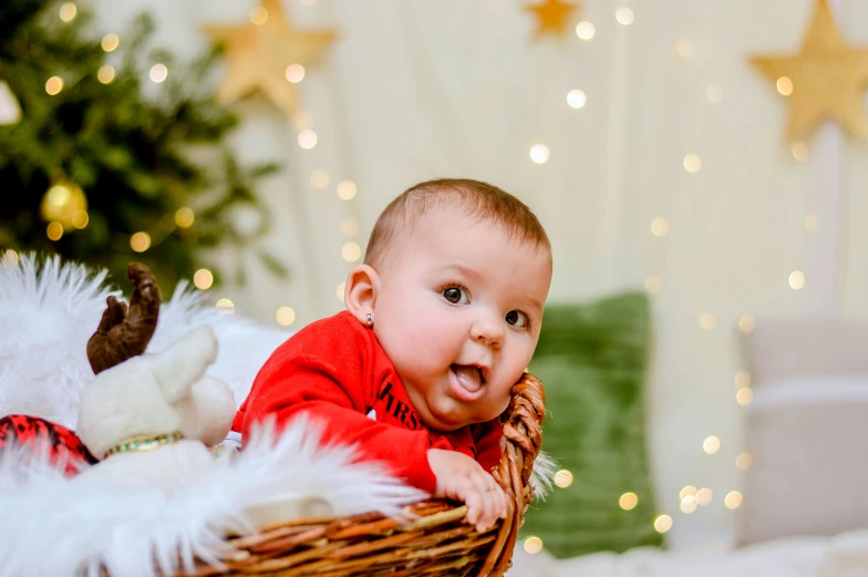 a baby sitting in a basket in front of a christmas tree, pexels contest winner, handsome, cherub, very surprised, owen gent