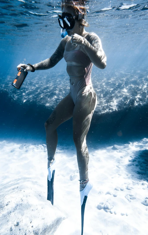 a woman in a wetsuit diving in the ocean, by Will Ellis, full body potrait holding bottle, high-quality photo, ultrawide image, with grey skin