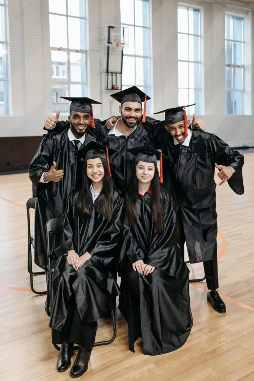 a group of people in graduation gowns posing for a picture, a portrait, pexels contest winner, indoor picture, black, promotional image, mechanics