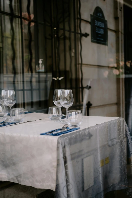 a table that has some wine glasses on it, by Raphaël Collin, unsplash, renaissance, inside a french cafe, linen, elegantly dressed, exterior shot