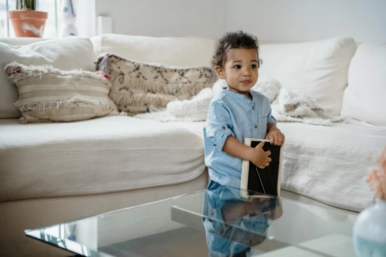 a little boy sitting on top of a glass table, an album cover, by Nina Hamnett, pexels contest winner, happening, luxurious wooden coffee table, holding a nintendo switch, riyahd cassiem, 2 years old