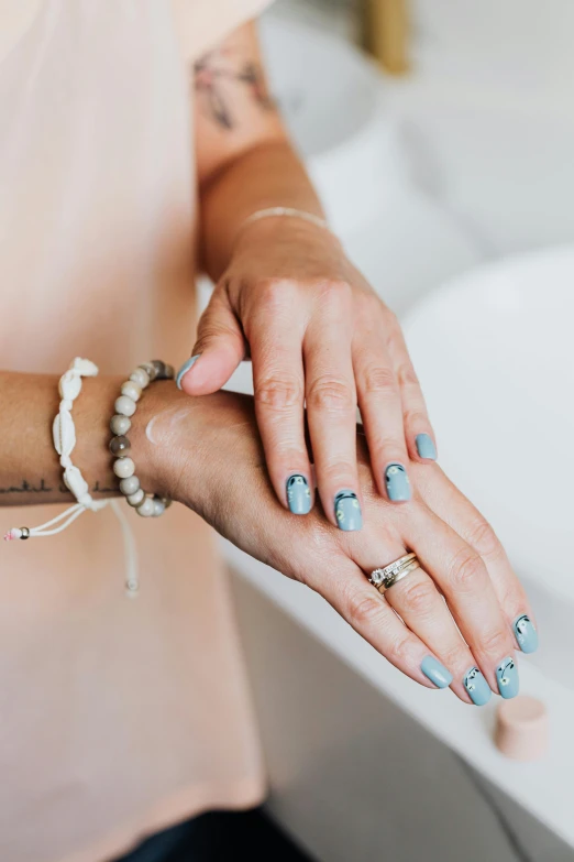 a woman getting ready to wash her hands, by Julia Pishtar, unsplash, aestheticism, white and teal metallic accents, wearing two silver bracelets!, marbling effect, coast