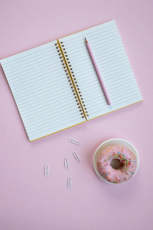 a cup of coffee and a donut on a pink background, by Nicolette Macnamara, pexels, lined paper, 15081959 21121991 01012000 4k, notebook, confetti