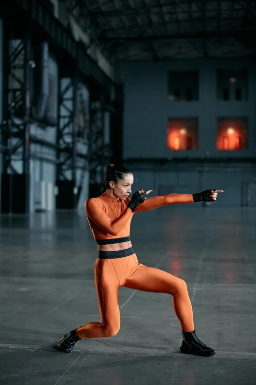 a woman in a wrestling stance while wearing all orange