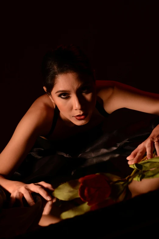 a woman laying in bed with a rose in her hand, an album cover, inspired by Horst Antes, mahira khan as a mage, candid!! dark background, oona chaplin, doing an elegant pose over you