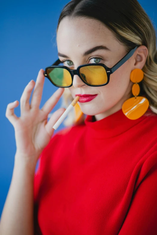 a woman wearing sunglasses and a red top, inspired by Bert Stern, trending on pexels, pop art, smoking, sydney sweeney, orange yellow, square glasses