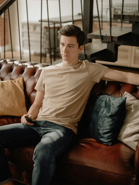 a man sitting on top of a brown couch, trending on reddit, androgynous male, wearing tight shirt, high-quality photo, profile image