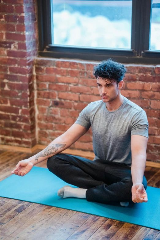 a man sitting on a yoga mat in front of a window, a portrait, trending on pexels, renaissance, zayn malik, square, inviting posture, focused photo