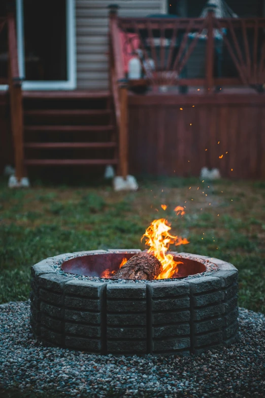 a fire pit sitting in the middle of a yard, pexels contest winner, lit from bottom, summer evening, burning building, grainy