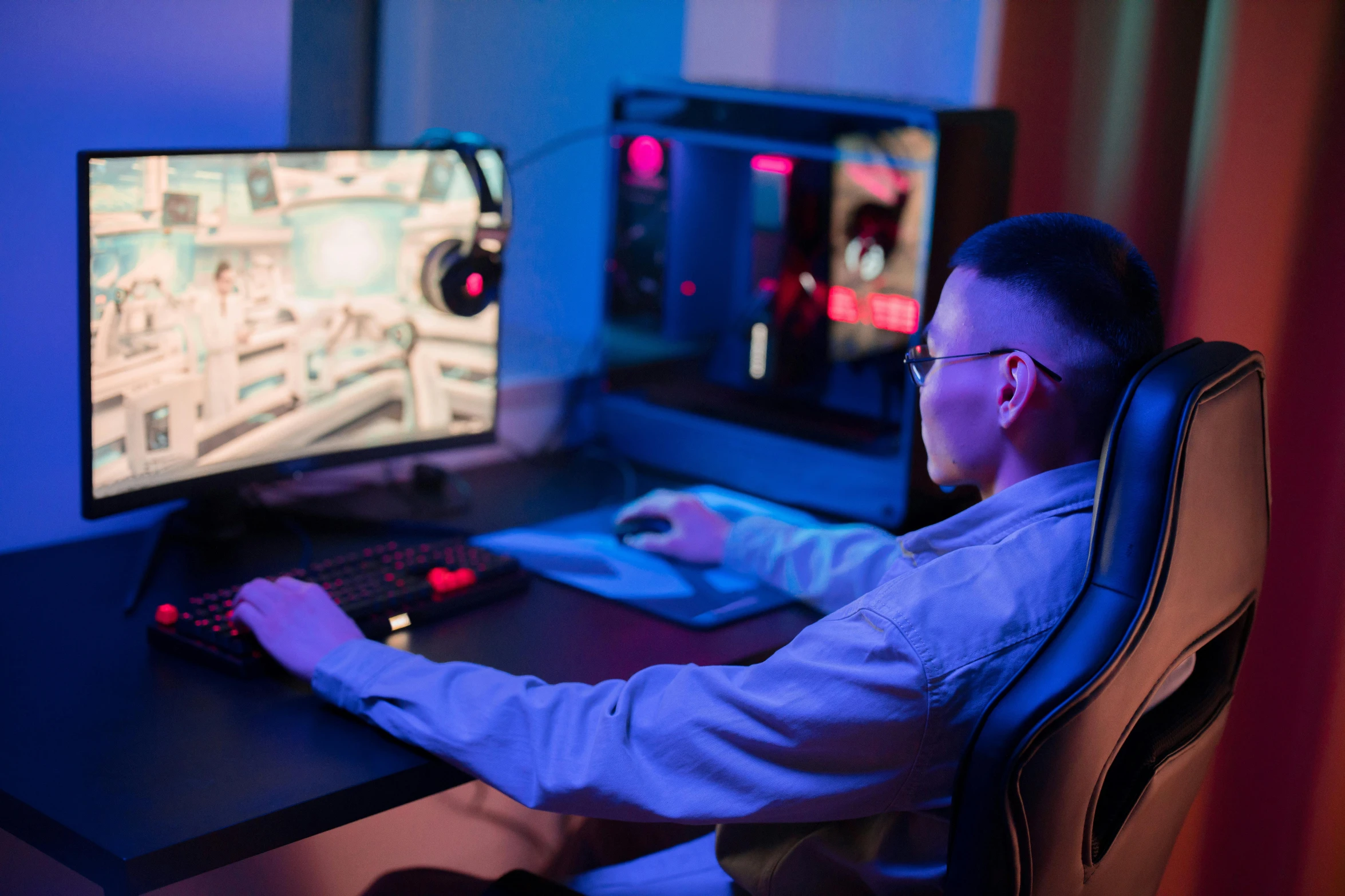 a man sitting in a chair in front of a computer, game resources, pink and blue lighting, profile picture 1024px, post+processing