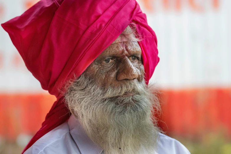 a man with a long beard wearing a red turban, by Bapu, pexels contest winner, white and pink cloth, lots of wrinkles, aboriginal, slightly pixelated