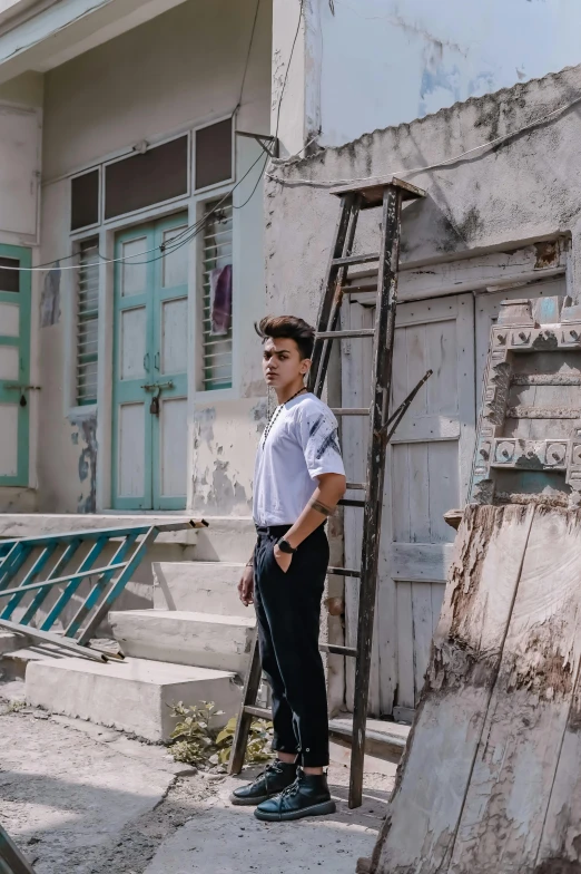 a young man standing in front of a building, a colorized photo, by Sam Dillemans, trending on unsplash, cuban setting, non binary model, wearing white shirt, in a village