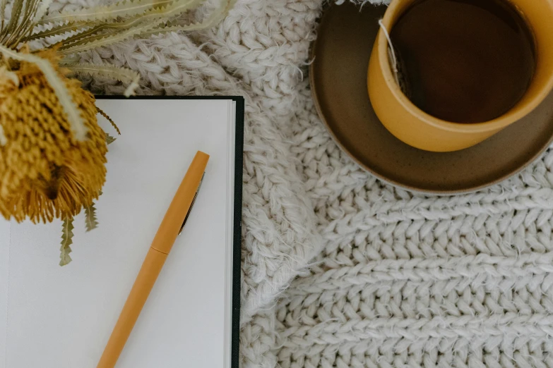 a cup of coffee and a notebook on a blanket, trending on pexels, yellow carpeted, background image, thumbnail, cottagecore