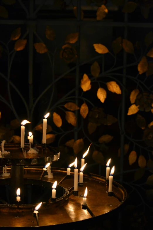 a group of lit candles sitting on top of a table, gold leaves, gothic lighting, spiralling, panels