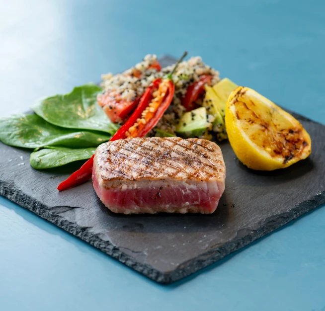 a close up of a plate of food on a table, fish in the background, profile image