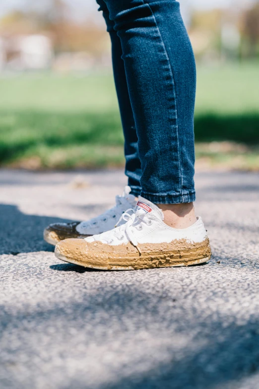 a close up of a person standing on a skateboard, by Julia Pishtar, rubber waffle outsole, straw, wearing white sneakers, dirt stains