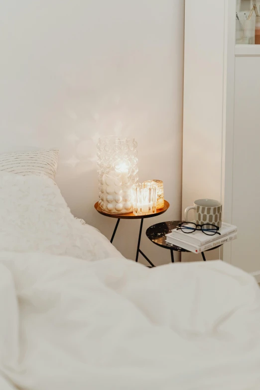 a bed room with a neatly made bed and a night stand, by Liza Donnelly, trending on pexels, light and space, white candles, with paper lanterns, white bg, ethereal soft and fuzzy glow