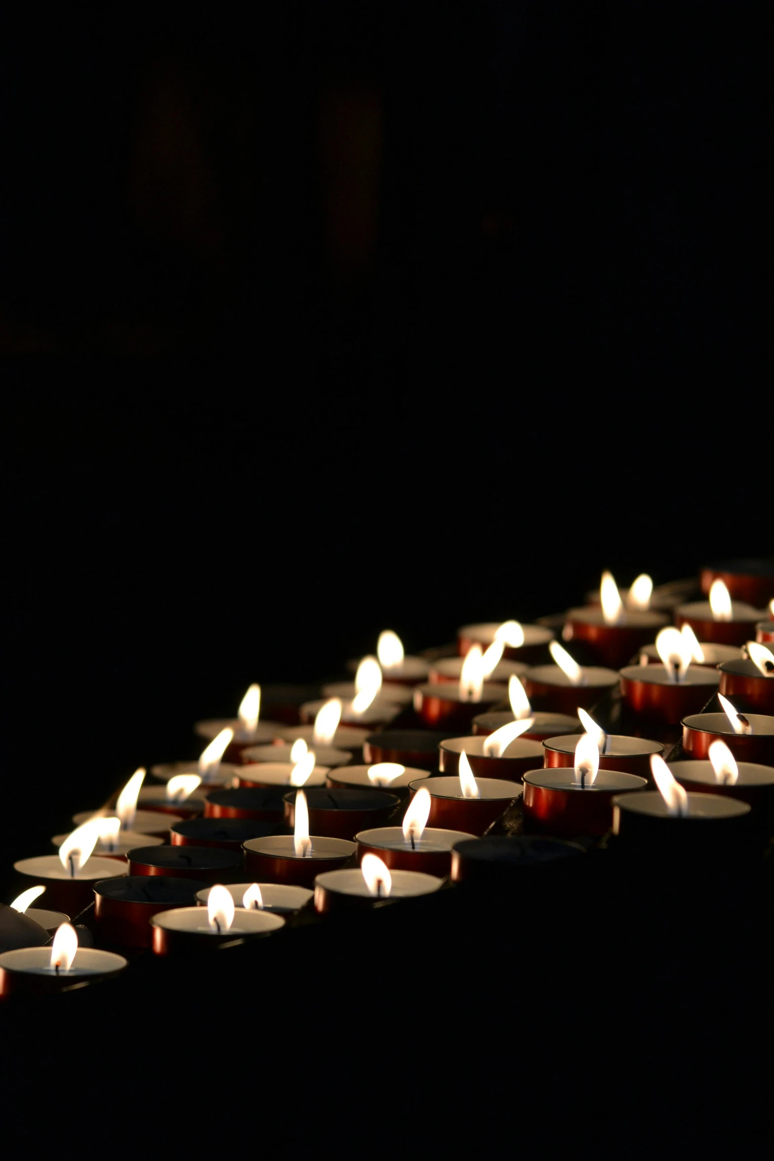 a row of lit candles in a dark room, sprawling, hundreds of them, noon, remembrance