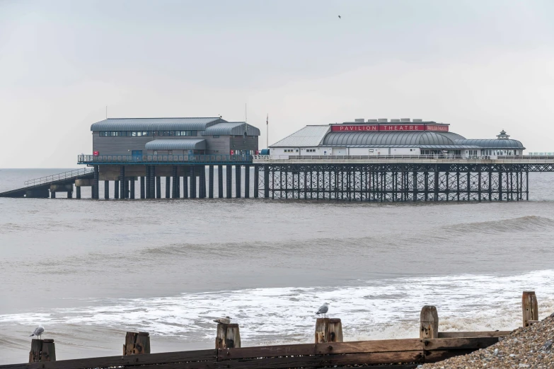 a pier sitting on top of a beach next to the ocean, by IAN SPRIGGS, shutterstock, a crystal palace, seen from a distance, hull, seals