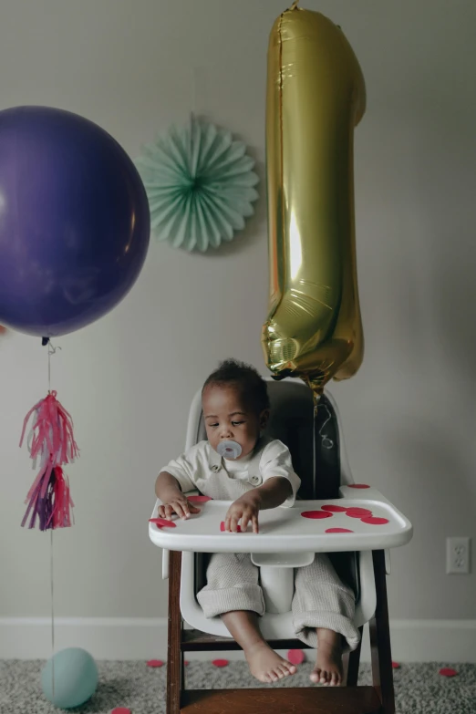 a baby sitting in a high chair in front of balloons, dark skinned, parties, gen z, medium-shot