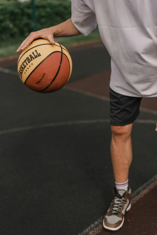 a man standing on a basketball court holding a basketball, trending on dribble, wearing shorts, zoomed out shot, off putting, schools