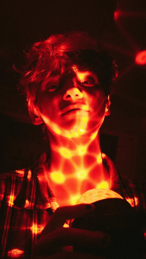 a close up of a person holding a cell phone, by David Donaldson, holography, red haired teen boy, flare, red leds, press shot