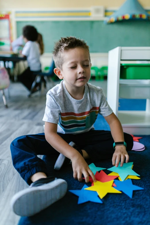 a little boy that is sitting on the floor, in a classroom, brain stars, thumbnail, puzzling