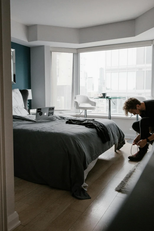 a man standing next to a bed in a bedroom, unsplash contest winner, behind the scenes photo, dwell, floor to ceiling window, taking a picture