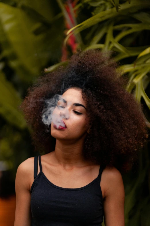 a woman in a black tank top smokes a cigarette, trending on pexels, long afro hair, lush foliage, smoke :6, whirling smoke