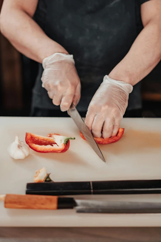 a person cutting a pepper on a cutting board, holding a knife, multiple stories, surgery, plastic wrap