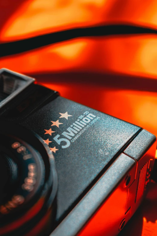 a close up of a camera on a table, by Mathias Kollros, black and orange, hollywood promotional image, icon, vivid and vibrant