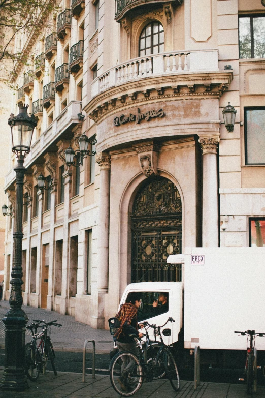 a white truck parked in front of a tall building, inspired by Tomàs Barceló, pexels contest winner, art nouveau, coffee shop, tall arched stone doorways, gif, gothic quarter