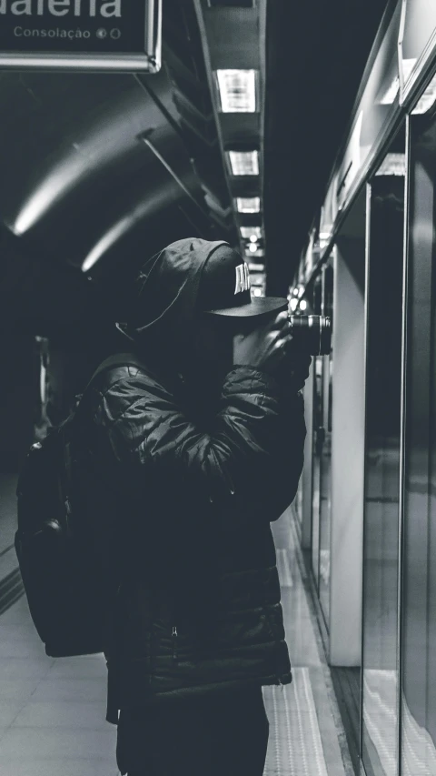 a black and white photo of a person standing on a subway platform, unsplash, graffiti, bank robbery, hooded, instagram photo, thumbnail