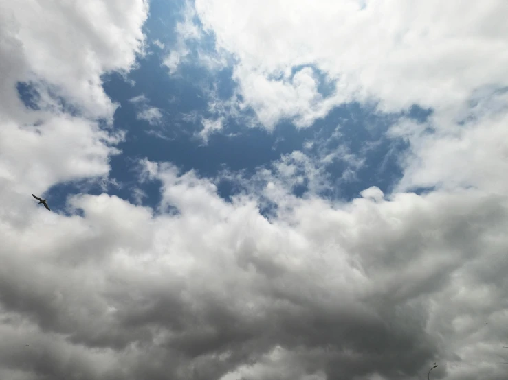 a plane flying through a cloudy blue sky, an album cover, unsplash, hurufiyya, layered stratocumulus clouds, today\'s featured photograph 4k, gray sky, show from below