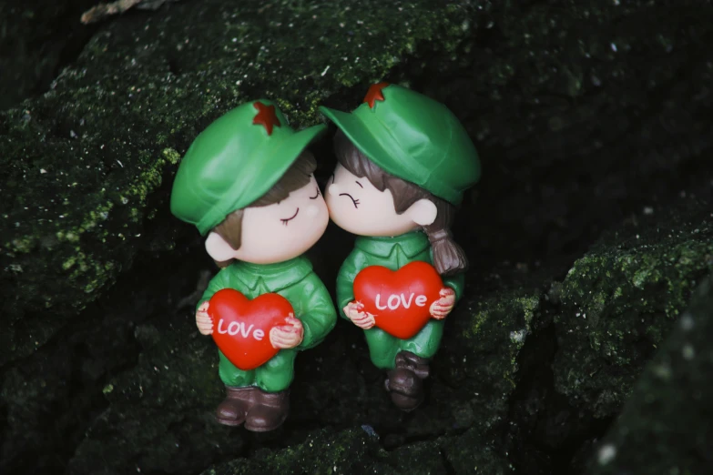 a couple of figurines sitting on top of a rock, a cartoon, by Valentine Hugo, pexels, wearing military outfit, romantic greenery, 千 葉 雄 大, love theme