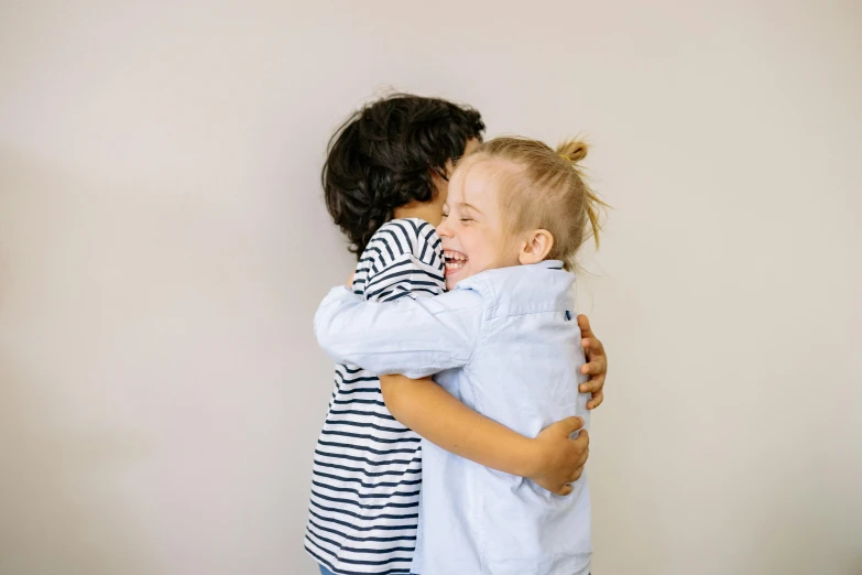 a couple of kids that are hugging each other, by Nina Hamnett, pexels, antipodeans, both laughing, bowater charlie and brom gerald, indoor picture, lachlan bailey