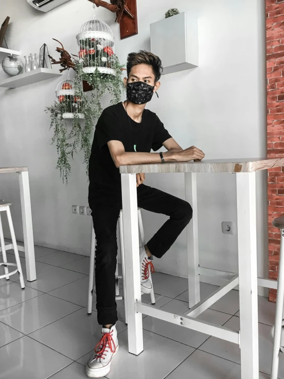 a man sitting at a table with a mask on, by Yosa Buson, instagram, full body picture, low quality photo, gif, casual black clothing