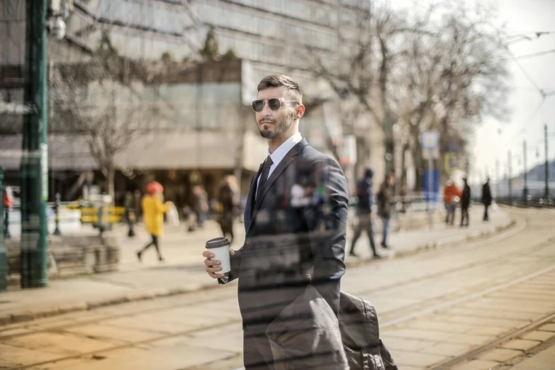 a man in a suit holding a cup of coffee, by Mathias Kollros, pexels contest winner, photorealism, walking to work, toronto, avatar image, real life photo of a syrian man