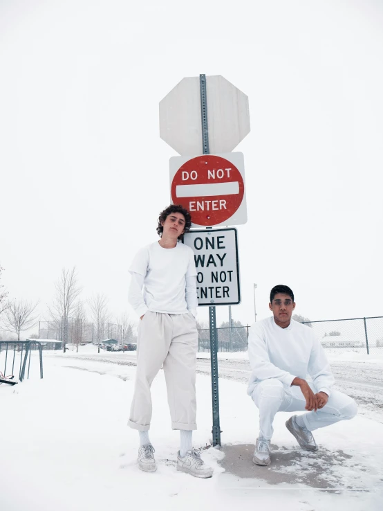 a couple of people standing next to a stop sign, an album cover, by Grace Polit, pexels contest winner, full body:: snow outside::, cute boys, white outfit, childhood friend vibes