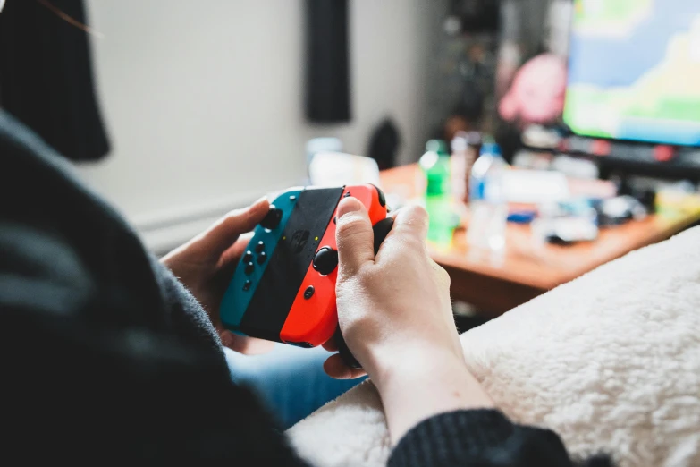 a person holding a nintendo wii game controller, by Julia Pishtar, trending on pexels, teenager hangout spot, valorant game style, brilliantly coloured, at home