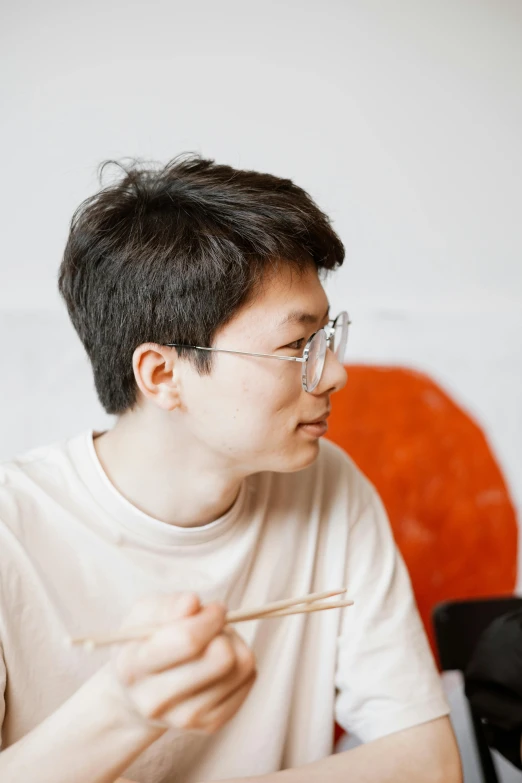 a man sitting at a table with chopsticks in his mouth, an album cover, inspired by Fei Danxu, trending on unsplash, mingei, john egbert, discord profile picture, student, candid portrait photo