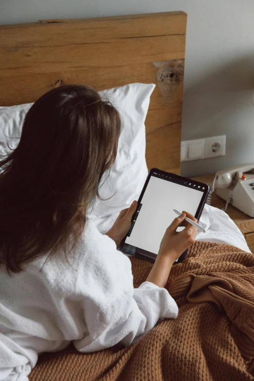 a woman sitting on a bed using a tablet computer, pexels contest winner, white sheets, digital pen and digital ink, brown, ux