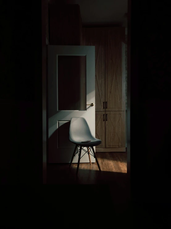 a chair sitting in the middle of a dark room, a picture, leaning on door