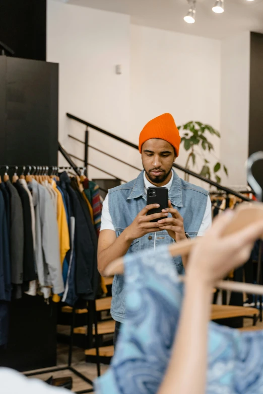 a man looking at his cell phone in a clothing store, a photo, trending on pexels, he is wearing a hat, bruh moment, gif, corrected