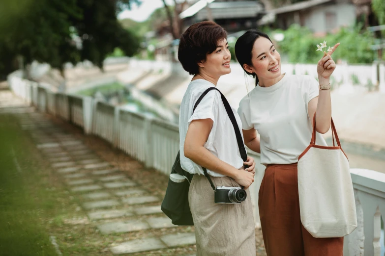 a couple of women standing next to each other, by Tan Ting-pho, pexels contest winner, happening, avatar image, korean woman, outdoor photo, over the shoulder